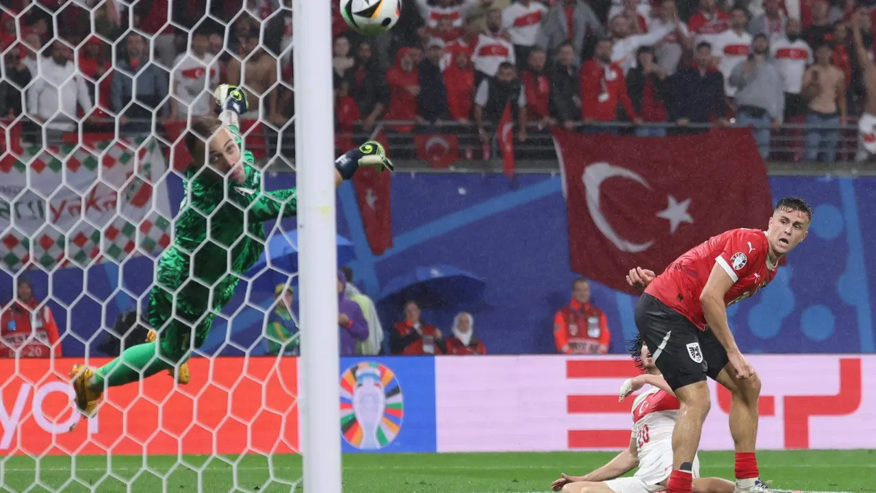 El portero turco Mert Gunok (i) salva un tiro de Christoph Baumgartner de Austria (d) durante el partido de fútbol de la Eurocopa 2024. EFE/EPA/CHRISTOPHER NEUNDORF